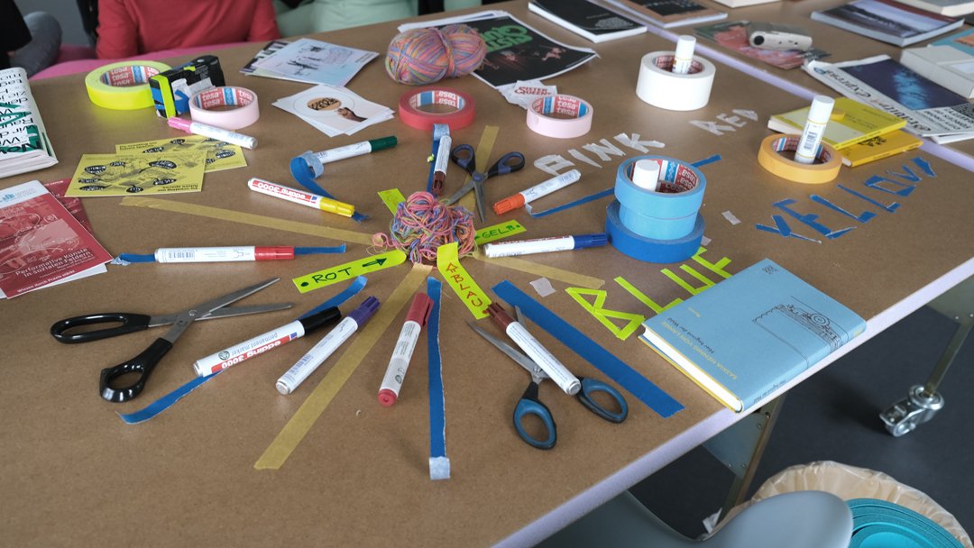 Auf einem Tisch sind Stifte, Notizzettel und Flyer angeordnet